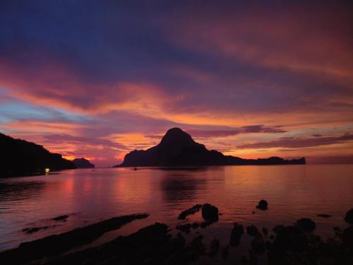 a sunset over a body of water with a mountain at Golden Monkey Beach Hotel in El Nido