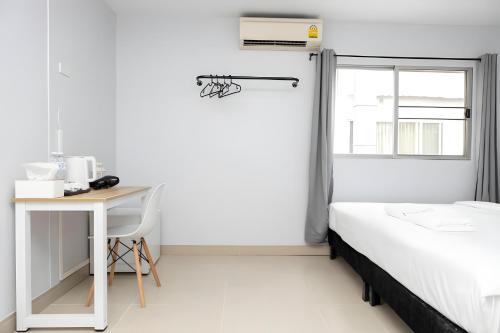 a bedroom with a bed and a desk and a window at Elite Hotel Nana Sukhumvit 3 in Bangkok