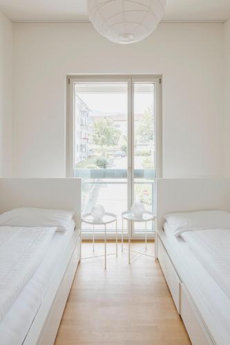 a white bedroom with two beds and a window at Apartment Löwengarten 26 in Rorschach