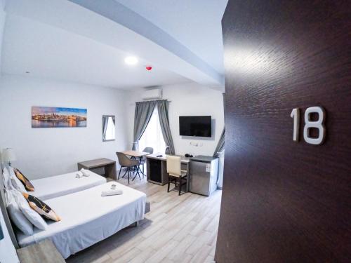 a hotel room with two beds and a desk at Napoli Suites Studios Aparthotel in St Julian's