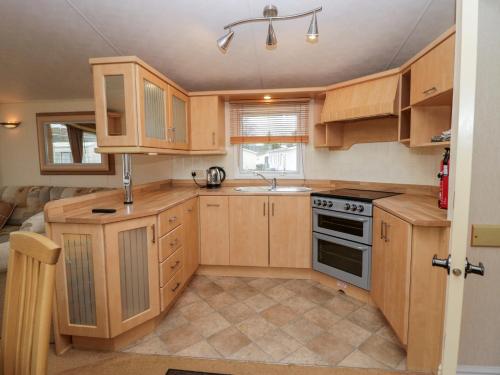 a small kitchen with wooden cabinets and a stove at Birch in Denny
