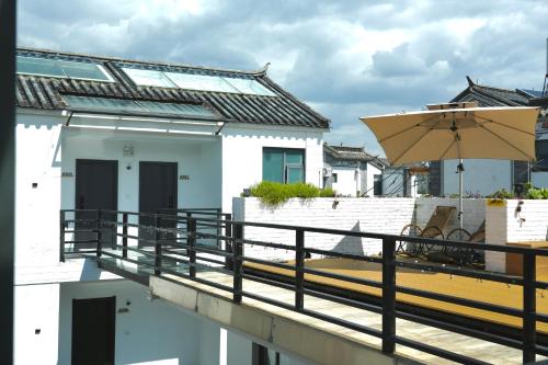 a balcony with an umbrella and a building at 叁三民宿 in Dali