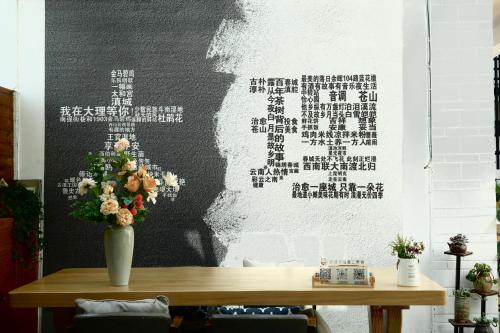 a table with a vase of flowers on a wall at 叁三民宿 in Dali