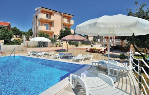 Una piscina con sillas y sombrillas al lado de un edificio. en Apartment Pavlinka Bb Iii, en Posedarje