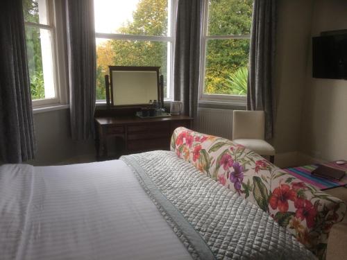 a bedroom with a bed and a couch and windows at The Brandize Guest House in Torquay