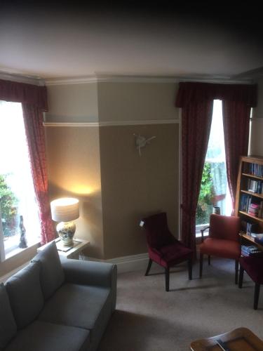 a living room with a couch and chairs and windows at The Brandize Guest House in Torquay