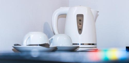 a white toaster sitting on a table with two dishes at Napoli Suites Studios Aparthotel in St Julian's