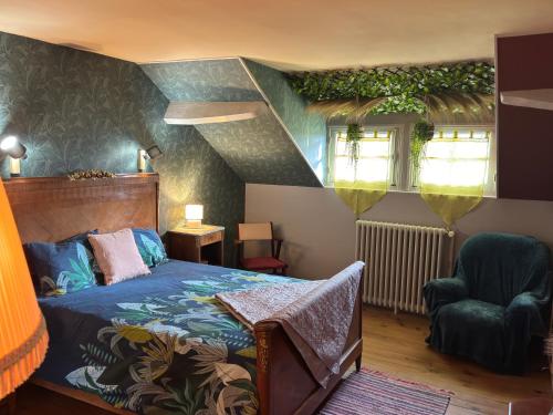 une chambre avec un lit et une chaise dans l'établissement Gîte de la petite fourmy, à Saint-Sulpice-les-Feuilles