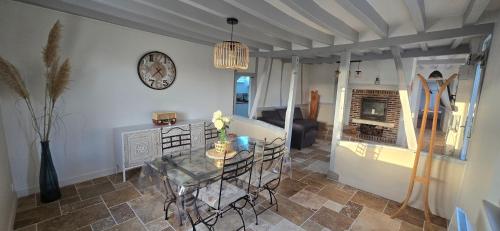 a living room with a table and a clock on the wall at Au Détour de Dampierre-en-Bray in Le Long Périer