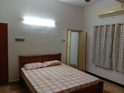 a bedroom with a bed and a window at Kallidai Home Stay Kumbakonam in Kumbakonam