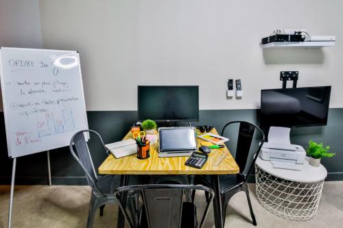 un bureau avec une table, un ordinateur portable et un tableau blanc dans l'établissement WS Louvre - Saint Honoré, à Paris