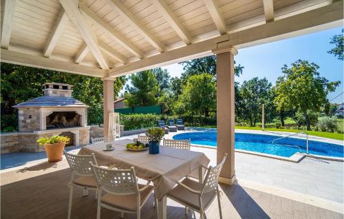 a patio with a table and a fireplace and a swimming pool at Villa Miana in Orbanići