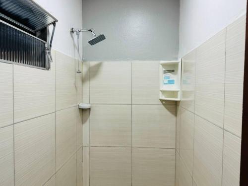 a shower in a bathroom with white tiles at Apto Grande Vitória in Manaus