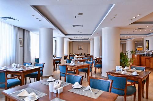 a restaurant with wooden tables and blue chairs at Swiss Inn Nile Hotel in Cairo