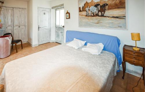 a bedroom with a blue bed and a painting on the wall at Nice Home In Venasque With Kitchen in Venasque