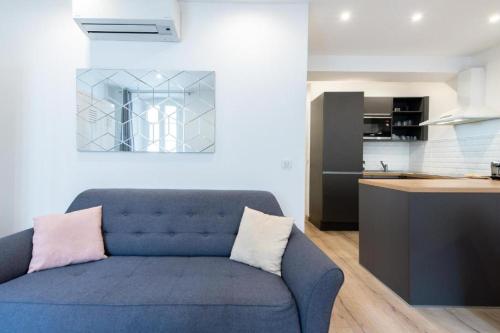 un salon avec un canapé bleu et une cuisine dans l'établissement LE NID DU SUQUET une escapade idéale pour couples, près commerces, Palais et plages, à Cannes