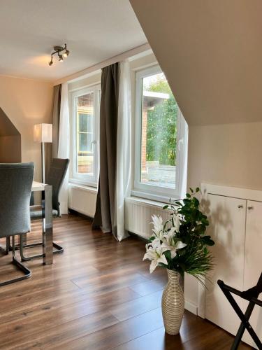 a living room with a vase of flowers on the floor at Airport Business Apartment in Norderstedt