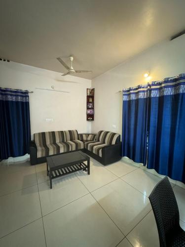a living room with couches and blue curtains at Zenways Retreat - Poovar in Pūvār