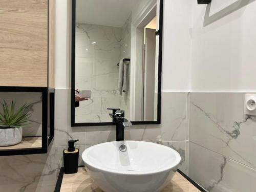 une salle de bain avec un lavabo blanc et une douche dans l'établissement La Seigneurerie Le Grand Studio, à Deauville