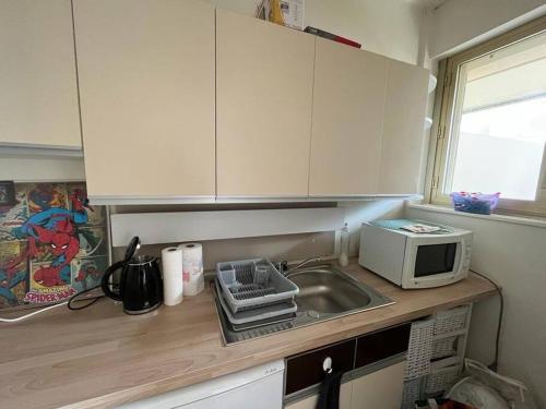 un comptoir de cuisine avec un évier et un micro-ondes dans l'établissement La Seigneurerie Le Grand Studio, à Deauville