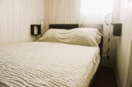 une chambre avec un lit blanc avec une fenêtre dans l'établissement Le Bridge Barcarès Clim Accès plage direct Parking Privé, au Barcarès