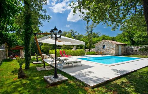 a pool with a table and an umbrella next to a house at Villa Stancija Bursic in Pula