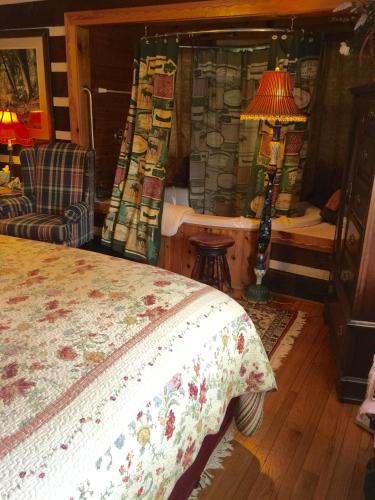 a bedroom with a bed and a lamp and a chair at Creekwalk Inn Bed and Breakfast with Cabins in Cosby