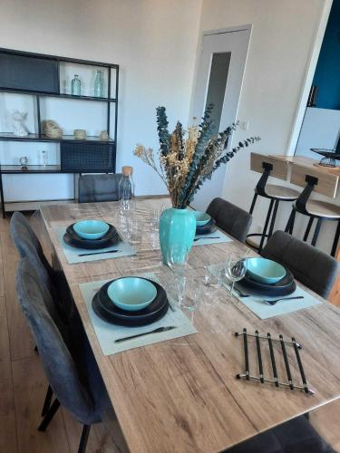une table en bois avec des assiettes et des verres bleus dans l'établissement Plage et Port à 2 Pas, à Fécamp