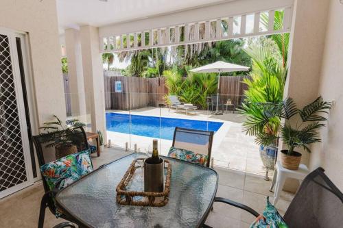 a glass table with a bottle of wine on a patio at Tropical 2 BR, 2 Bath Villa with private pool in Palm Cove