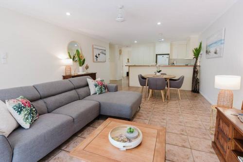 a living room with a gray couch and a kitchen at Tropical 2 BR, 2 Bath Villa with private pool in Palm Cove