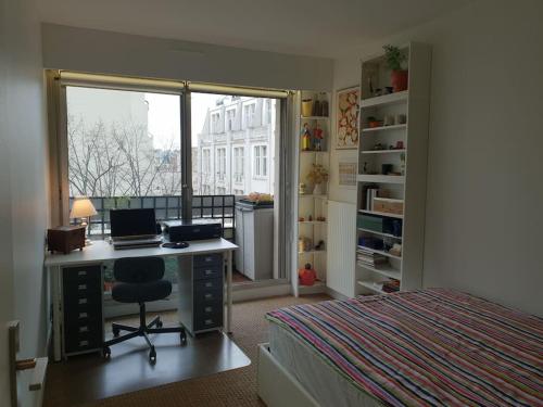 パリにあるAlesia - Plantesの机とベッドと窓のある寝室