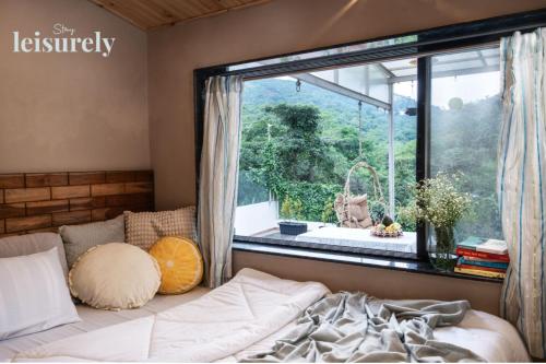 une chambre avec un lit et une grande fenêtre dans l'établissement Stay Leisurely Pawna Lake Villa 3BHK, Pawna Lake, à Malavli