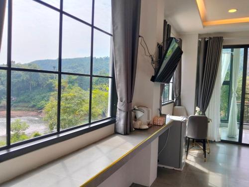 a room with large windows and a desk with a monitor at Kiree River Hotel โรงแรมคิรีริเวอร์ in Ban Thong Pha Phum