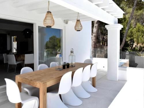 a dining room with a wooden table and white chairs at Villa in Ibiza with Sea Views and Jacuzzi in Es Cubells