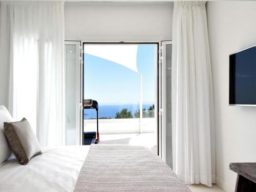 a bedroom with a bed and a sliding glass door at Villa in Ibiza with Sea Views and Jacuzzi in Es Cubells