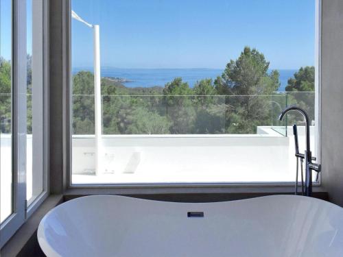 a white bath tub in front of a large window at Villa in Ibiza with Sea Views and Jacuzzi in Es Cubells