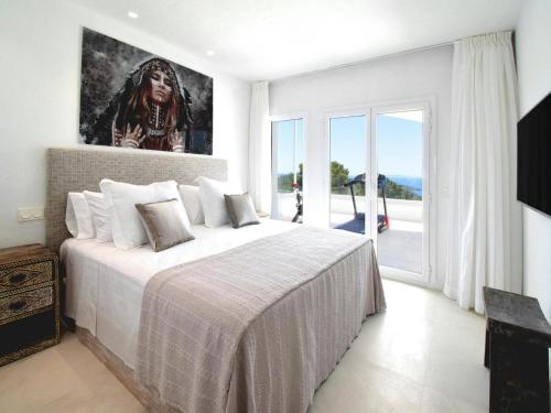 a bedroom with a large bed and a large window at Villa in Ibiza with Sea Views and Jacuzzi in Es Cubells