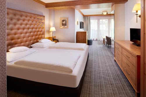 a hotel room with a large bed and a television at Sporthotel Ellmau in Tirol in Ellmau