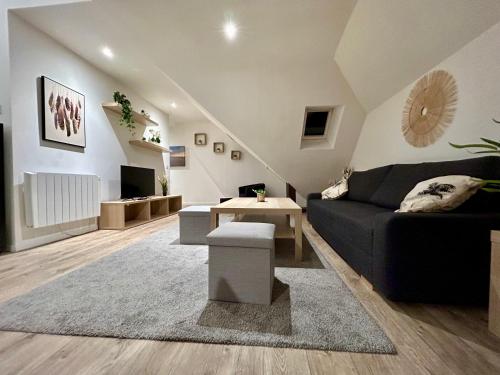 a living room with a black couch and a table at Appartement T.3 - Bord de mer in Ouistreham