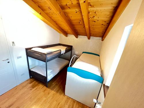 a small room with two beds and a wooden ceiling at Sonhozinho House Colico in Colico