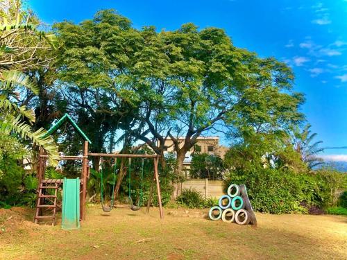 a playground with a swing set and a tree at Seaside Retreat in Kenton-on-Sea in Kenton on Sea