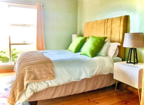 a bedroom with a bed with green pillows and a window at Seaside Retreat in Kenton-on-Sea in Kenton on Sea