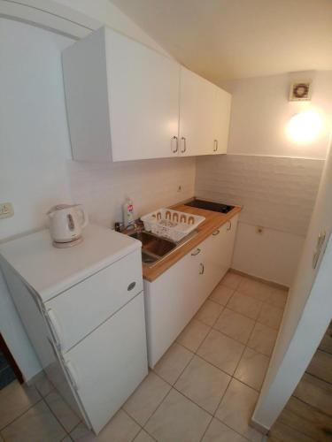 a small kitchen with white cabinets and a sink at Apartment Svetka in Sali