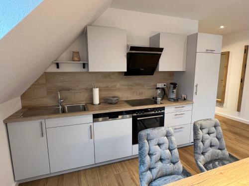 a kitchen with white cabinets and two chairs at Apartment Hof Düker, 2 Komfort DZ, Design Bad in Gütersloh
