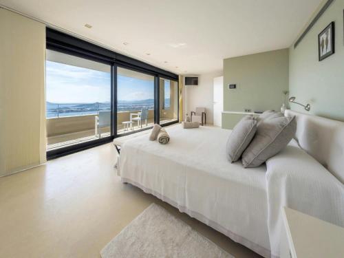 Un dormitorio con una cama blanca y una ventana grande. en Villa in Ibiza with Panoramic Sea Views, en Nuestra Señora de Jesús
