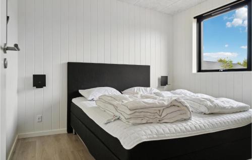 a bedroom with a bed with a black headboard and a window at 6 Bedroom Nice Home In Glesborg in Glesborg