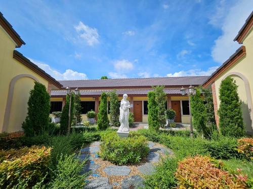 a garden with a statue in front of a building at CottagePine Rayong Resort&Cafe in Ban Ko Kloi