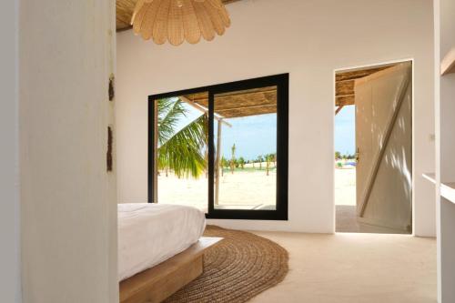 a bedroom with a bed and a view of the beach at OKAÏ Oasis Desert Senegal in Lompoul