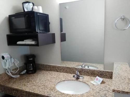 a bathroom with a sink and a tv and a mirror at Travelodge by Wyndham Dexter in Dexter
