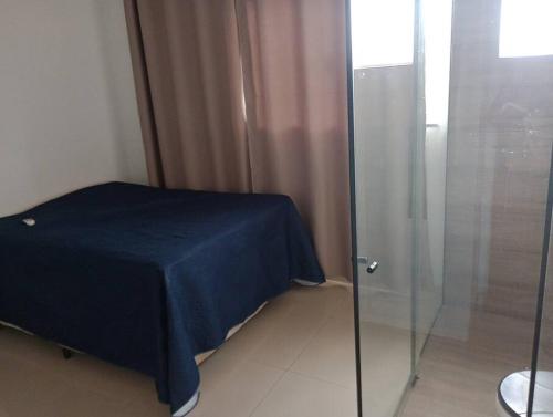 a bedroom with a glass shower with a blue sheet at quarto com ar condicionado in Jaboticabal
